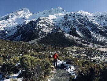 Rear view of people on footpath by snowcapped mountains