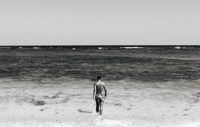 Rear view of man walking on shore at beach