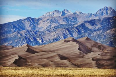 Scenic view of mountains and sand dunes against sky