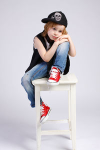 Girl wearing hat sitting against white background