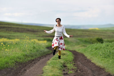 Full length of woman with arms raised on field