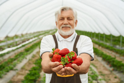 Young woman holding strawberry outdoors