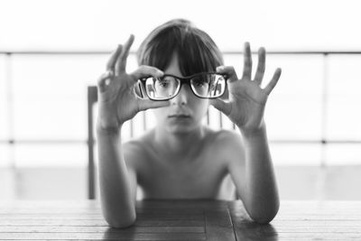 Portrait of shirtless boy holding eyeglasses