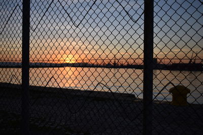 Full frame shot of chainlink fence against sky during sunset