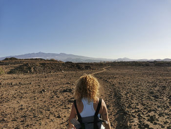 Rear view of woman standing on land against sky