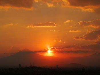 Scenic view of silhouette mountains against orange sky