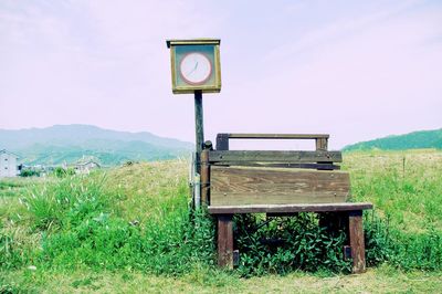 Empty bench on field against sky