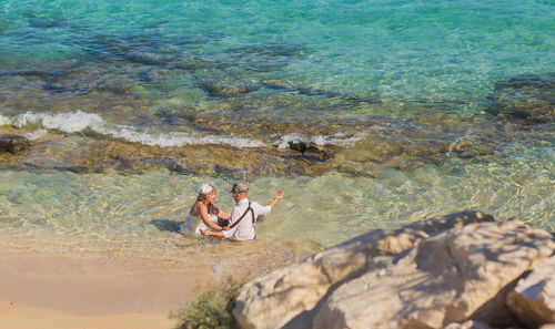 High angle view of people on rock by sea