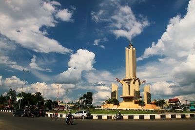 Road passing through city against cloudy sky