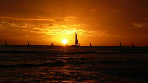 Silhouette sailboat sailing on sea against sky during sunset