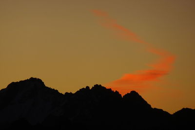 Low angle view of silhouette mountain against orange sky