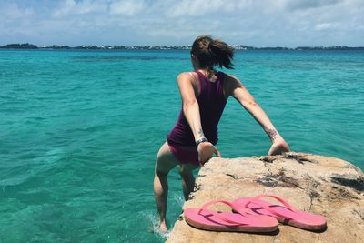 Slippers by woman diving in sea against sky