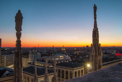 Aerial view of buildings against dramatic sky at sunset