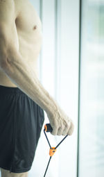 Shirtless man exercising by window