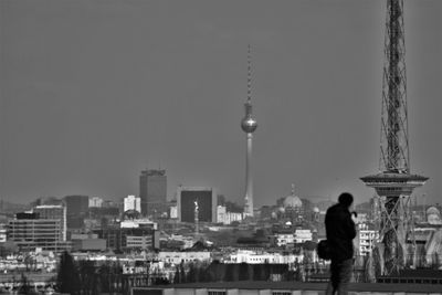 Rear view of man standing against fernsehturm in city