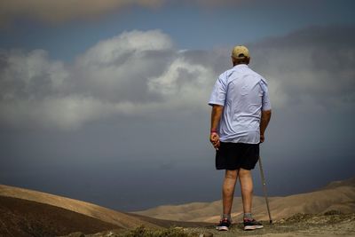 Rear view of man standing in sea against sky