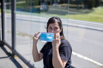 Woman at bus stop putting mask on her face