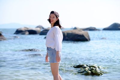 Full length portrait of young woman standing on beach