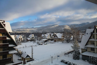 Panoramic view of townscape and snowcapped mountains against sky