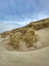 Scenic view of sand dunes at the beach against sky 