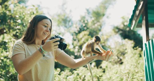 Young woman holding camera while standing on land