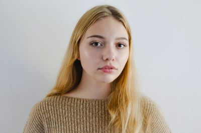 Portrait of beautiful young woman standing against white background