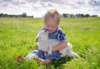 Little boy enjoys sweet puppy kisses as he holds a wiggly pup 