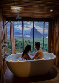 Couple sitting in bathtub while looking at landscape