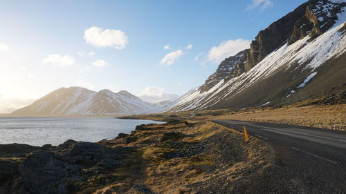 Panoramic view of snowcapped mountains by sea against sky