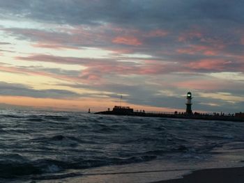 Lighthouse at baltic sea against cloudy sky during sunset