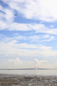 Low angle view of airplane flying over sea against sky