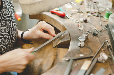 Cropped image of senior craftsperson making jewelry in workshop