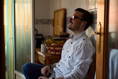 A young man listens to music with his headphones sitting at home