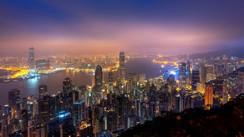 Illuminated buildings in city against sky at night