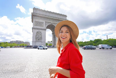 Portrait of young fashion woman walking in paris with arc de triomphe, france