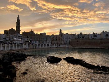 Buildings at waterfront during sunset