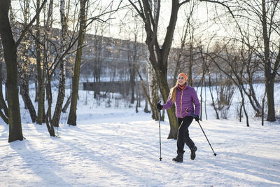 Woman with hiking pole walking on snow during winter