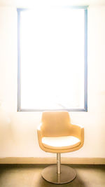 Empty chair and table against wall at home