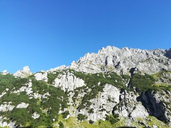 Low angle view of rocks against clear blue sky