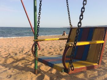 Swing at sandy beach against sky