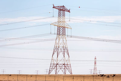 Low angle view of electricity pylon on field against sky