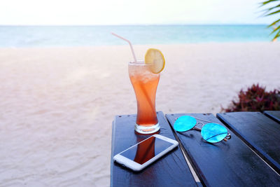 Close-up of drink and mobile phone on table at beach