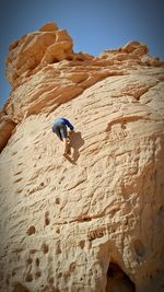 Low angle view of man on rock formation against sky