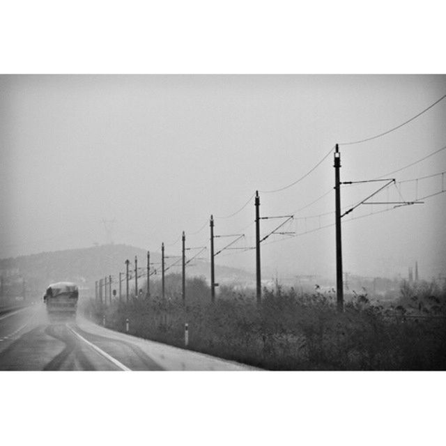 transfer print, transportation, auto post production filter, road, sky, clear sky, electricity pylon, landscape, field, road marking, day, power line, mode of transport, connection, outdoors, copy space, no people, car, fuel and power generation, street