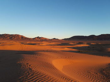 Scenic view of desert against clear blue sky