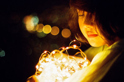 Portrait of girl holding illuminated christmas lights