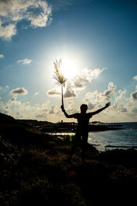 Silhouette person standing by sea against sky during sunset