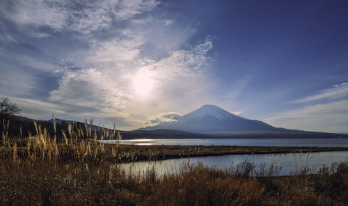Scenic view of lake by snowcapped mountains against sky