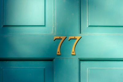 House number 77 on a turquoise wooden front door in london