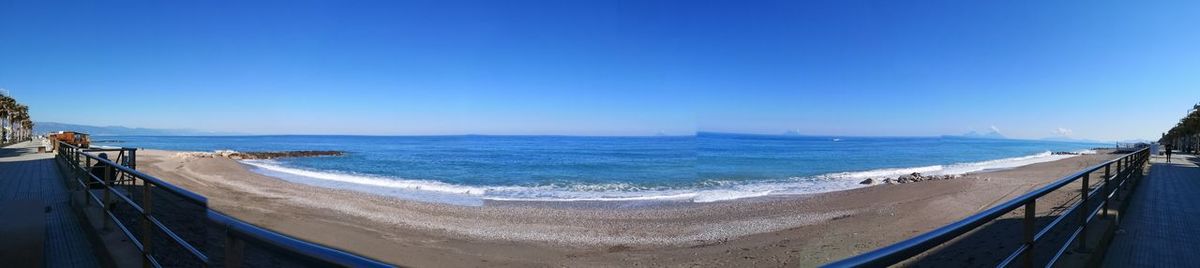 Panoramic view of beach against clear blue sky